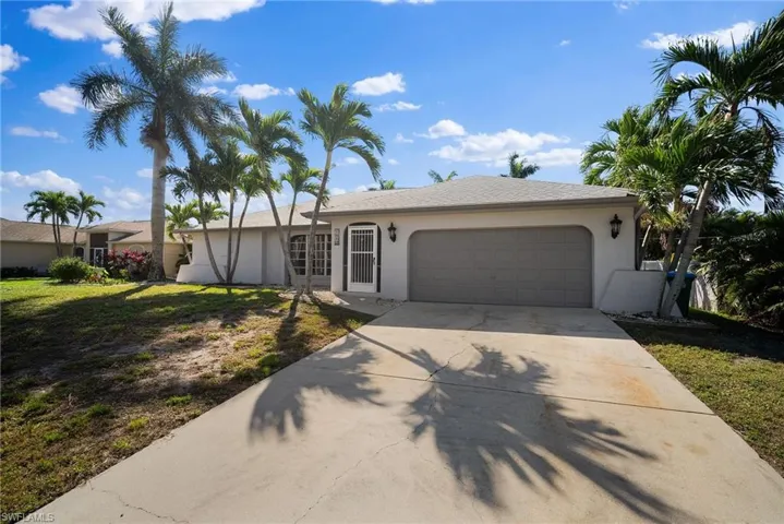 Single story home featuring driveway, a front lawn, an attached garage, and stucco siding