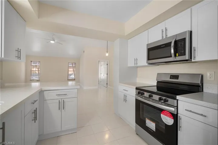 Kitchen with white cabinets, ceiling fan, appliances with stainless steel finishes, a peninsula, and light countertops
