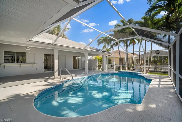 Pool featuring glass enclosure and a patio