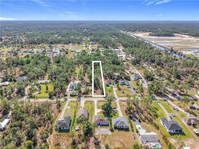 Aerial perspective of suburban area with a forest and a large body of water