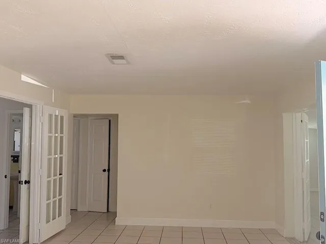 Empty room with a textured ceiling and light tile patterned floors