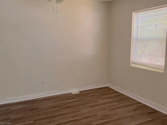 Spare room featuring dark wood-type flooring and baseboards
