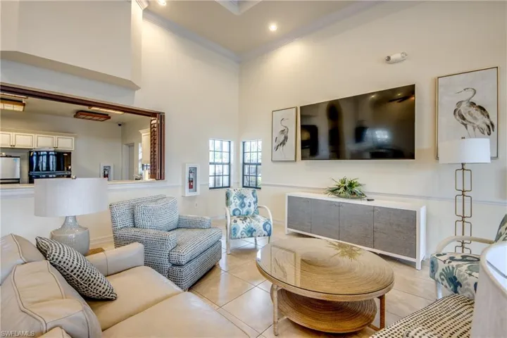 Vaulted ceilings with recessed lighting, tile flooring, and a large pass-through window opening to the kitchen