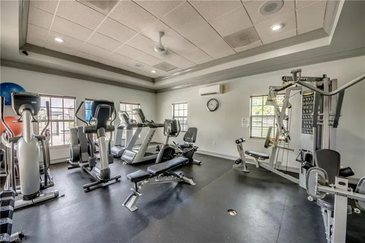 Fitness room featuring a tray ceiling, recessed lighting, rubberized flooring, and multiple windows