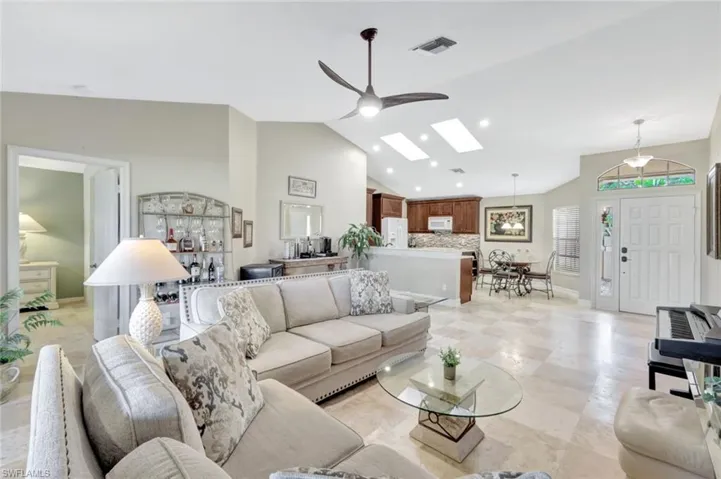 Living room featuring ceiling fan and vaulted ceiling with skylight