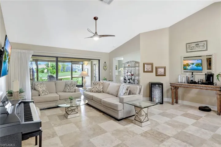 Living room featuring ceiling fan and high vaulted ceiling
