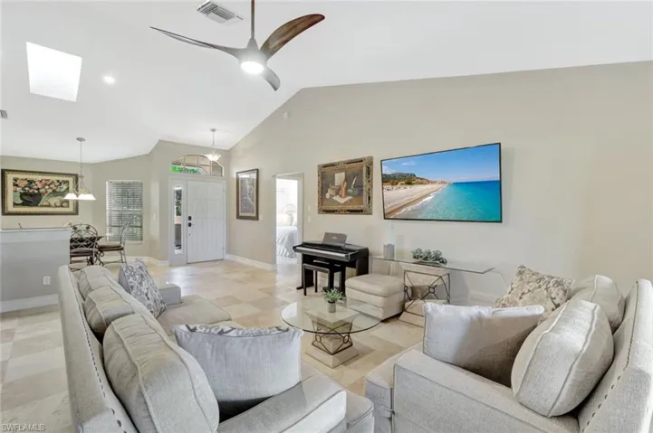Living room with ceiling fan and lofted ceiling with skylight