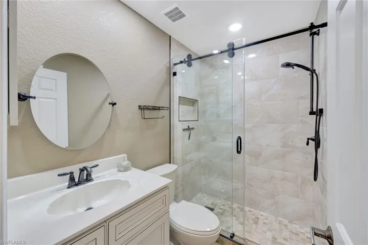 Bathroom with vanity, a shower with shower door, and toilet
