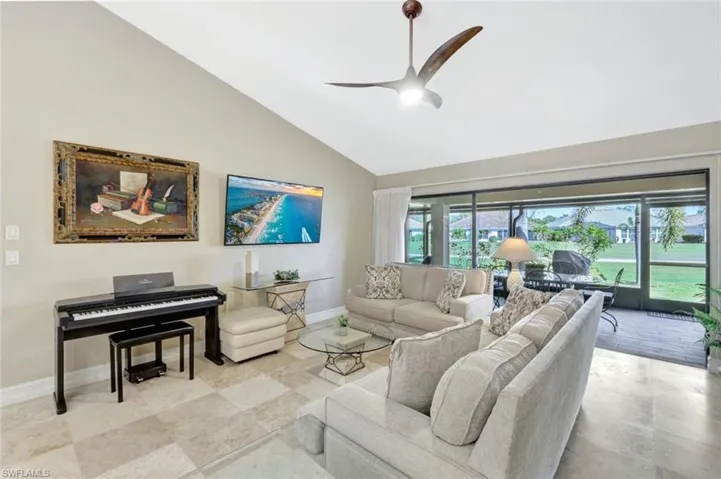 Living room featuring ceiling fan and high vaulted ceiling