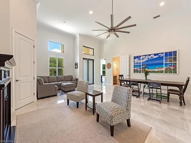 Living room with ornamental molding, ceiling fan, a high ceiling, light marble finish flooring, and recessed lighting
