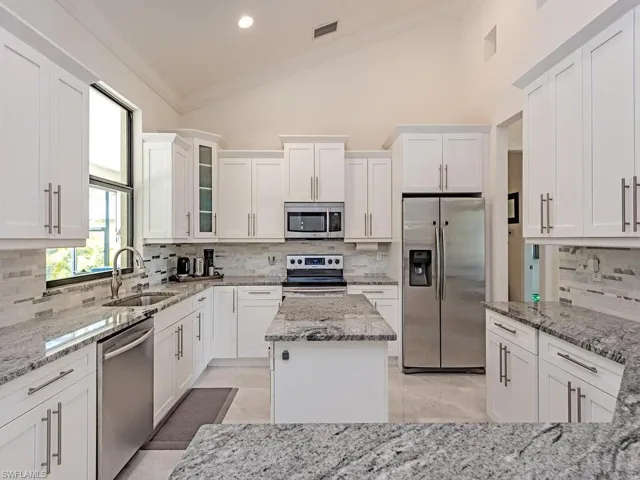 Kitchen featuring appliances with stainless steel finishes, a sink, tasteful backsplash, white cabinetry, and ornamental molding