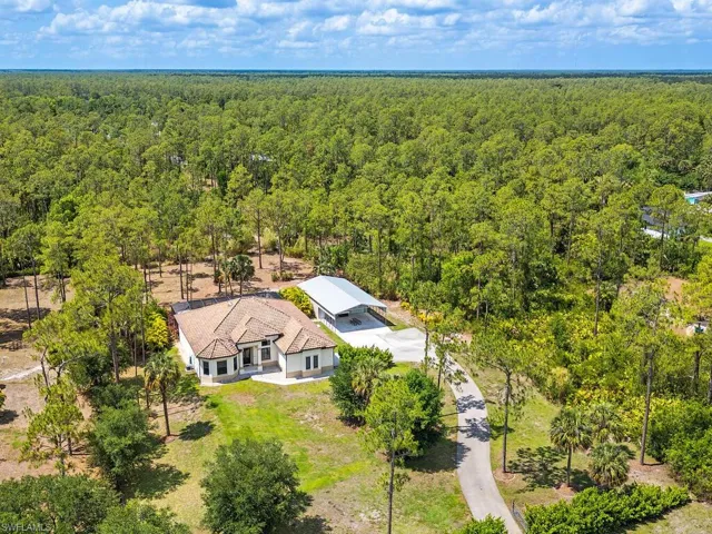 Aerial view of property and surrounding area featuring a forest