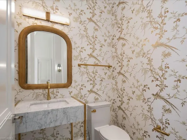 Half bath with wallpapered walls, a sink, and toilet