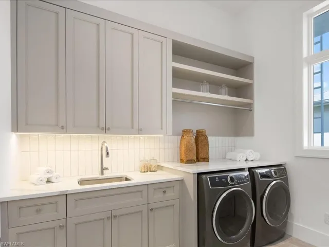 Washroom with washer and clothes dryer, cabinet space, a sink, and baseboards