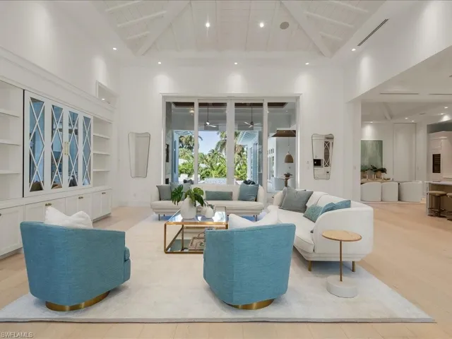 Living area featuring wood finished floors, built in shelves, recessed lighting, beam ceiling, and a high ceiling