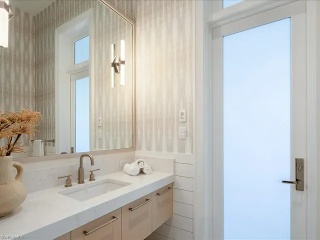 Bathroom with wallpapered walls and vanity