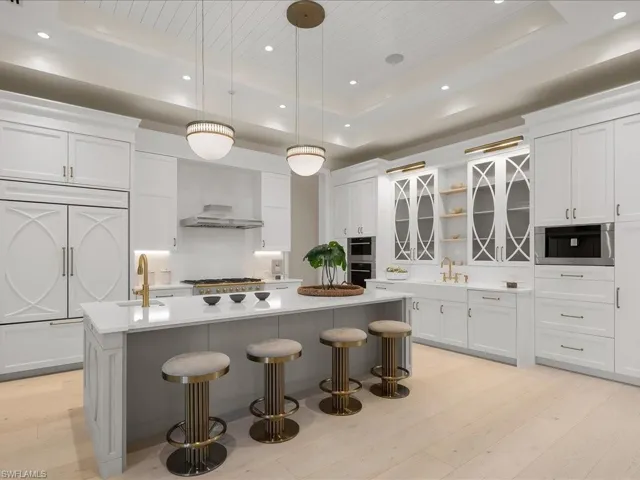 Kitchen with a sink, a tray ceiling, and light wood finished floors