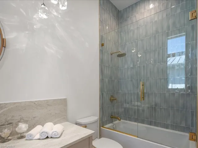 Full bathroom with bath / shower combo with glass door and toilet