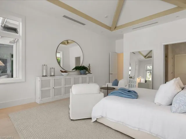 Bedroom with high vaulted ceiling, visible vents, beamed ceiling, baseboards, and wood finished floors