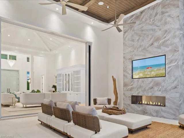 Living area featuring a fireplace, a high ceiling, wooden ceiling, and ceiling fan