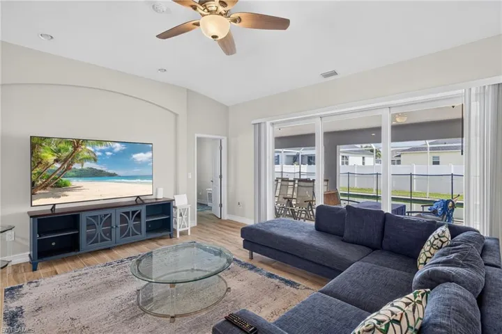 Spacious living area featuring light wood-finish flooring, recessed lighting, and a ceiling fan