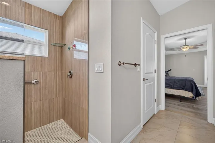 Walk-in shower featuring wood-finish tile walls, a patterned shower floor, and a clear glass enclosure
