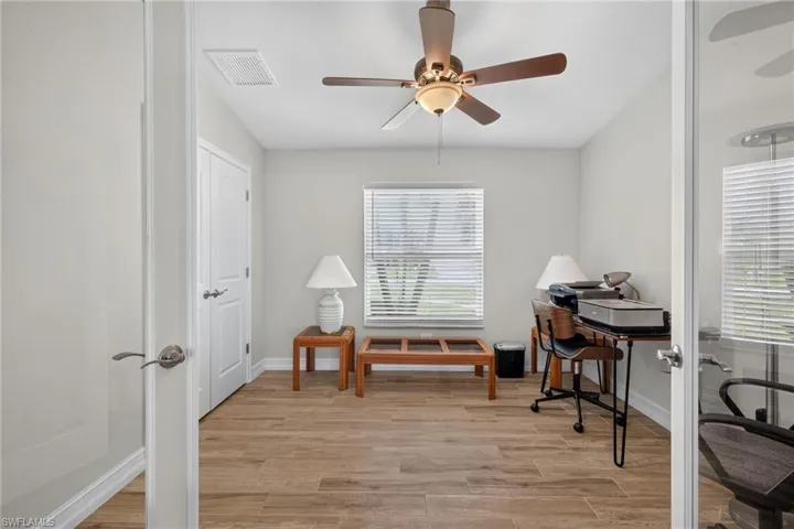 Bright room featuring wood-look tile flooring, a ceiling fan with integrated lighting, and a window with horizontal blinds