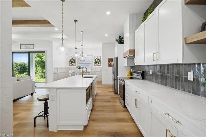 Kitchen featuring stainless steel appliances, tasteful backsplash, white cabinets, and light wood-type flooring