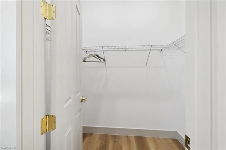 Walk in closet with wood-type flooring
