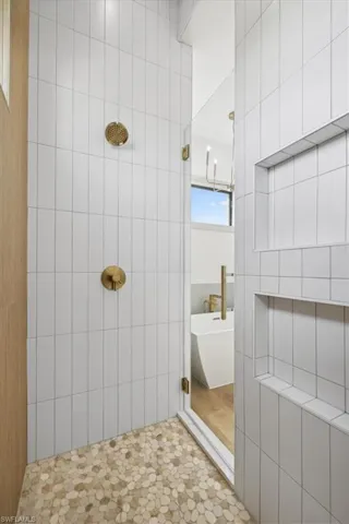 Bathroom with tiled shower, tile flooring, and tile walls