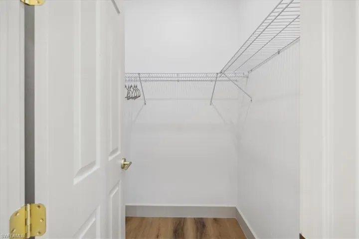 Walk in closet with hardwood / wood-style flooring