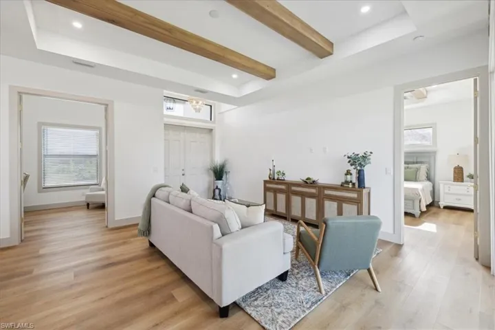 Living room with beam ceiling, light hardwood / wood-style flooring, and a raised ceiling