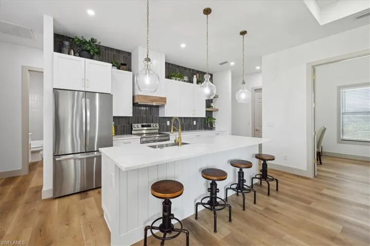 Kitchen with stainless steel appliances, white cabinetry, and light hardwood / wood-style floors