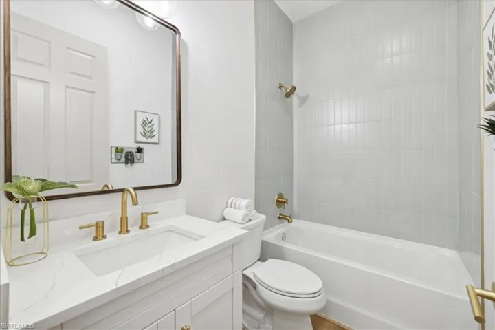 Full bathroom with tiled shower / bath, vanity, and toilet