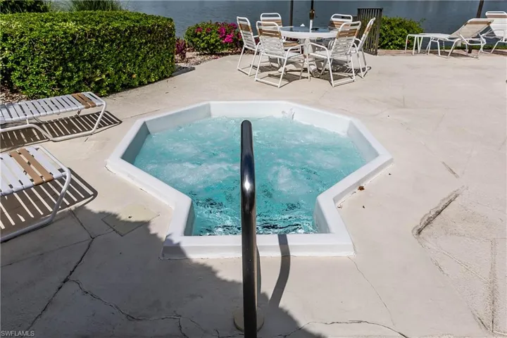 View of swimming pool featuring a patio, an in-ground hot tub, and a water view