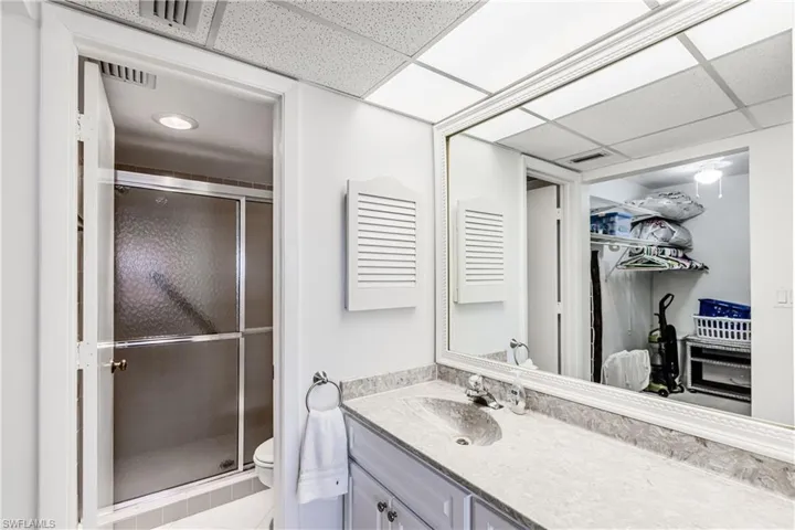 Full bathroom featuring a shower stall, vanity, a walk in closet, tile patterned floors, and a drop ceiling