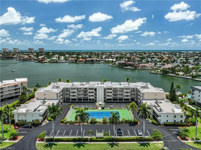 Drone / aerial view of a nearby body of water and apartment complex / building