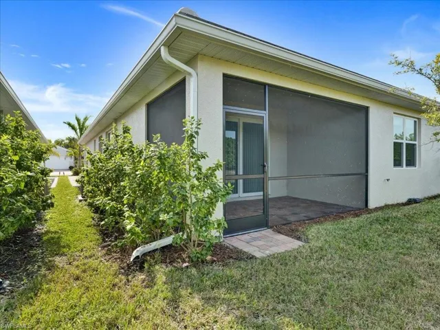 View of home's exterior featuring a sunroom, stucco siding, and a yard