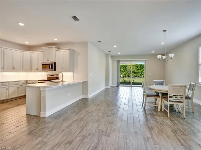 Kitchen featuring decorative light fixtures, stainless steel appliances, wood tiled floors, recessed lighting, and backsplash