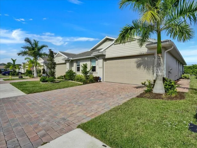 Single story home featuring a front yard, decorative driveway, and an attached garage