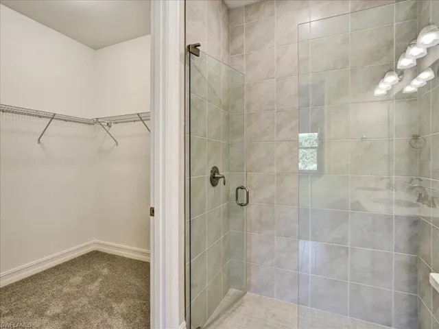 Full bath featuring a walk in closet, carpet floors, and a shower stall