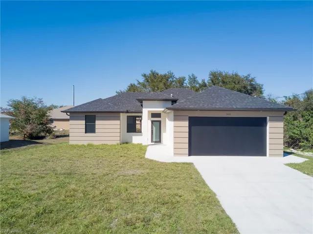 Prairie-style house featuring a front lawn, a garage, driveway, and roof with shingles