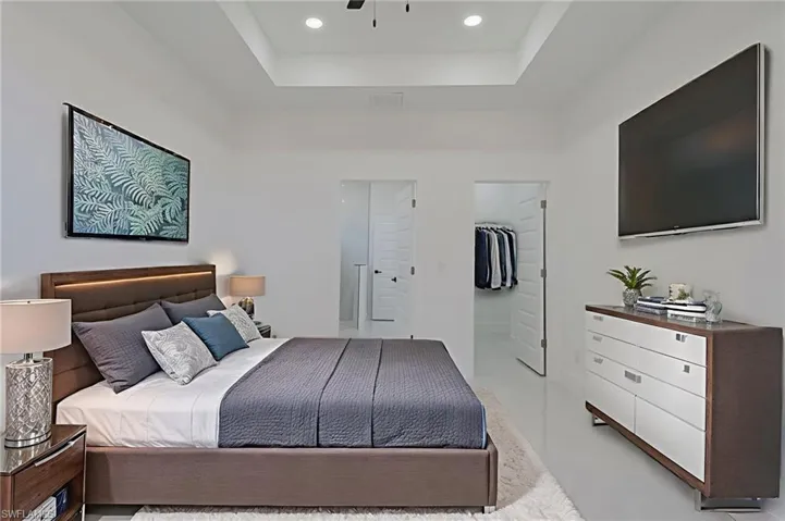 Bedroom featuring a walk in closet, ceiling fan, a raised ceiling, and recessed lighting