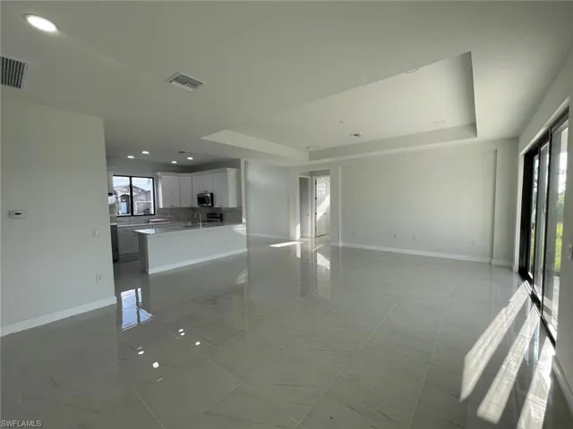 Unfurnished living room with light tile patterned floors and a tray ceiling
