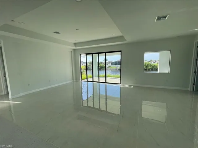 Tiled spare room with a water view and a tray ceiling