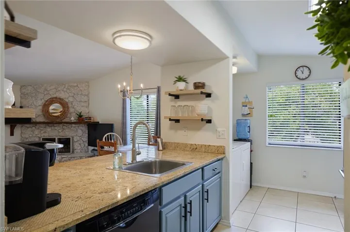 Kitchen featuring blue cabinets, dishwasher, a chandelier, light tile patterned flooring, and a fireplace