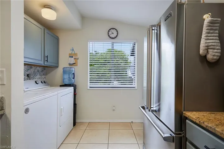 Laundry area with washer and dryer, cabinet space, and light tile patterned flooring