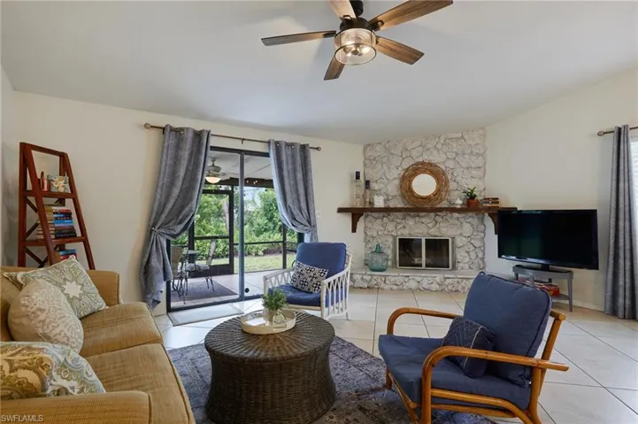 Living area featuring lofted ceiling, light tile patterned floors, ceiling fan, and a fireplace