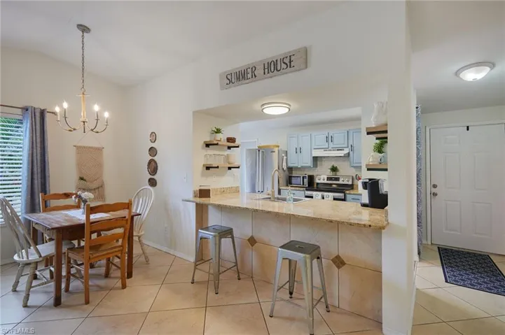 Kitchen with stainless steel appliances, under cabinet range hood, a peninsula, light tile patterned flooring, and a chandelier