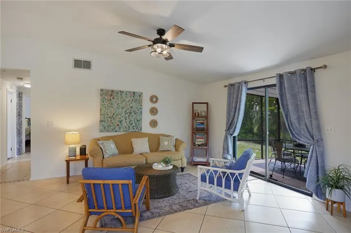 Living area with lofted ceiling, tile patterned flooring, and a ceiling fan